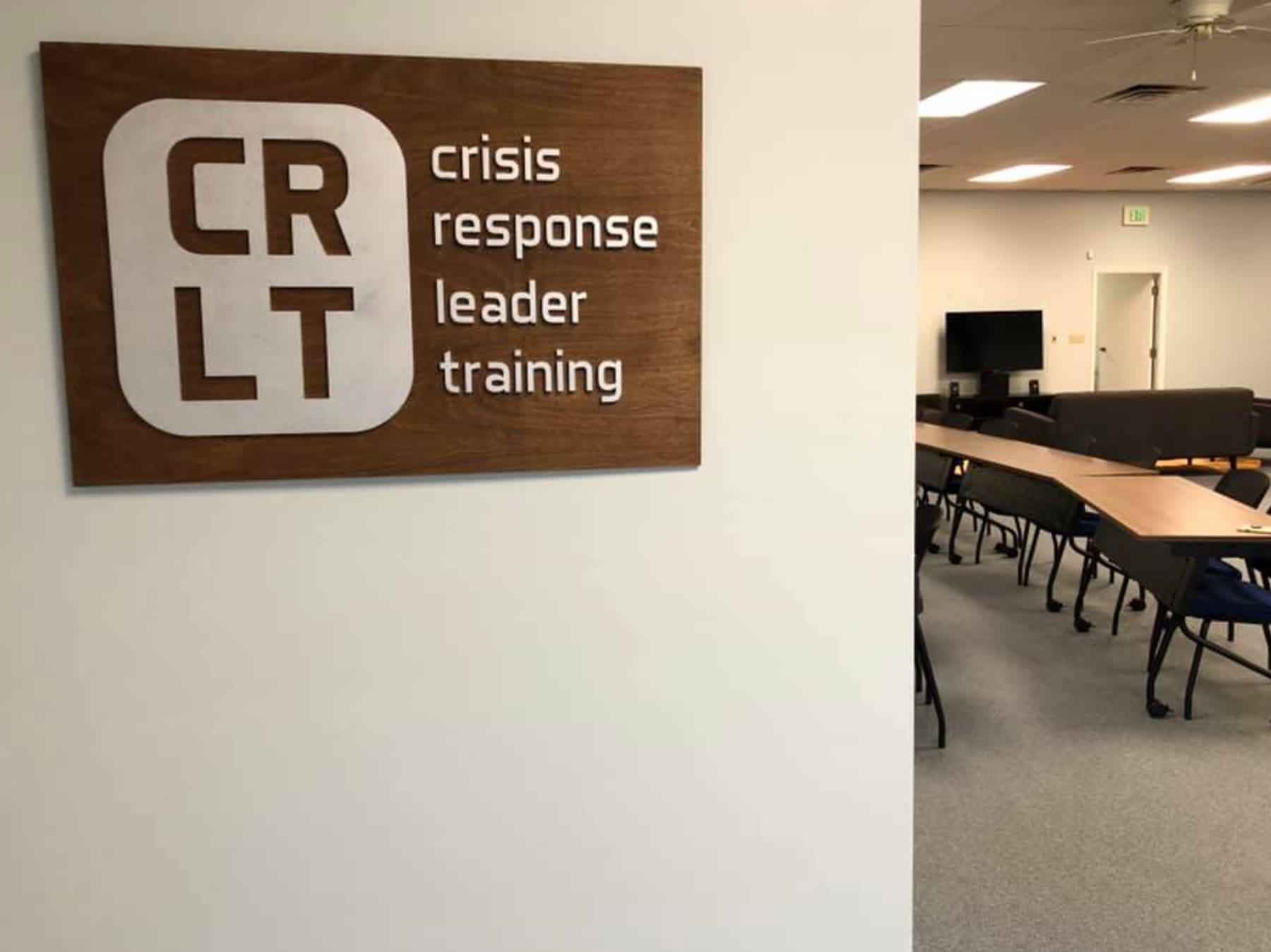 Wood wall sign for Crisis Response Leader Training beside a training room.